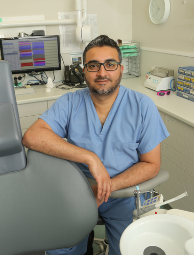 Dentist sits beside dental chair