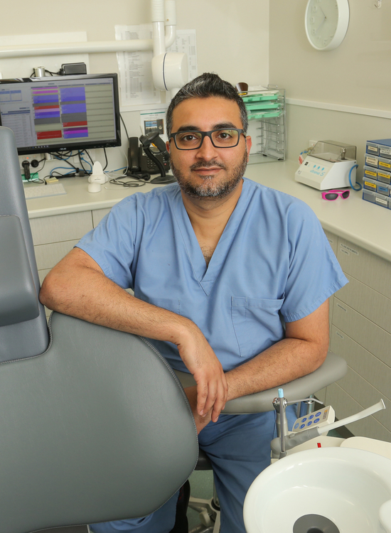 Dentist sits beside dental chair