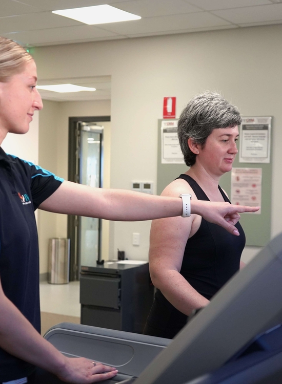 Exercise physiologist guides woman on treadmill