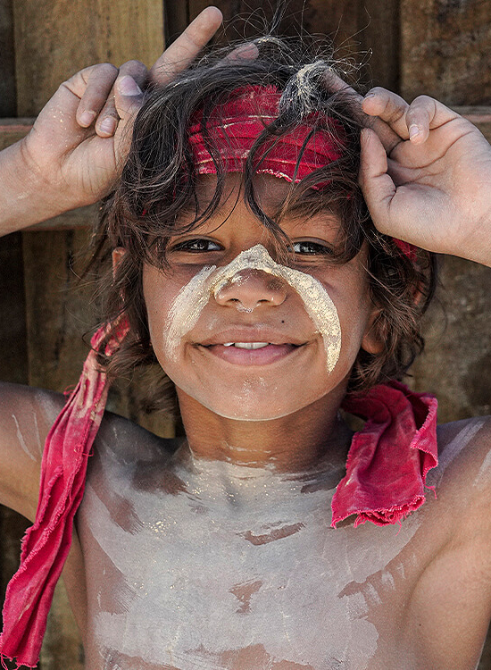 Young indigenous boy with white paint across face