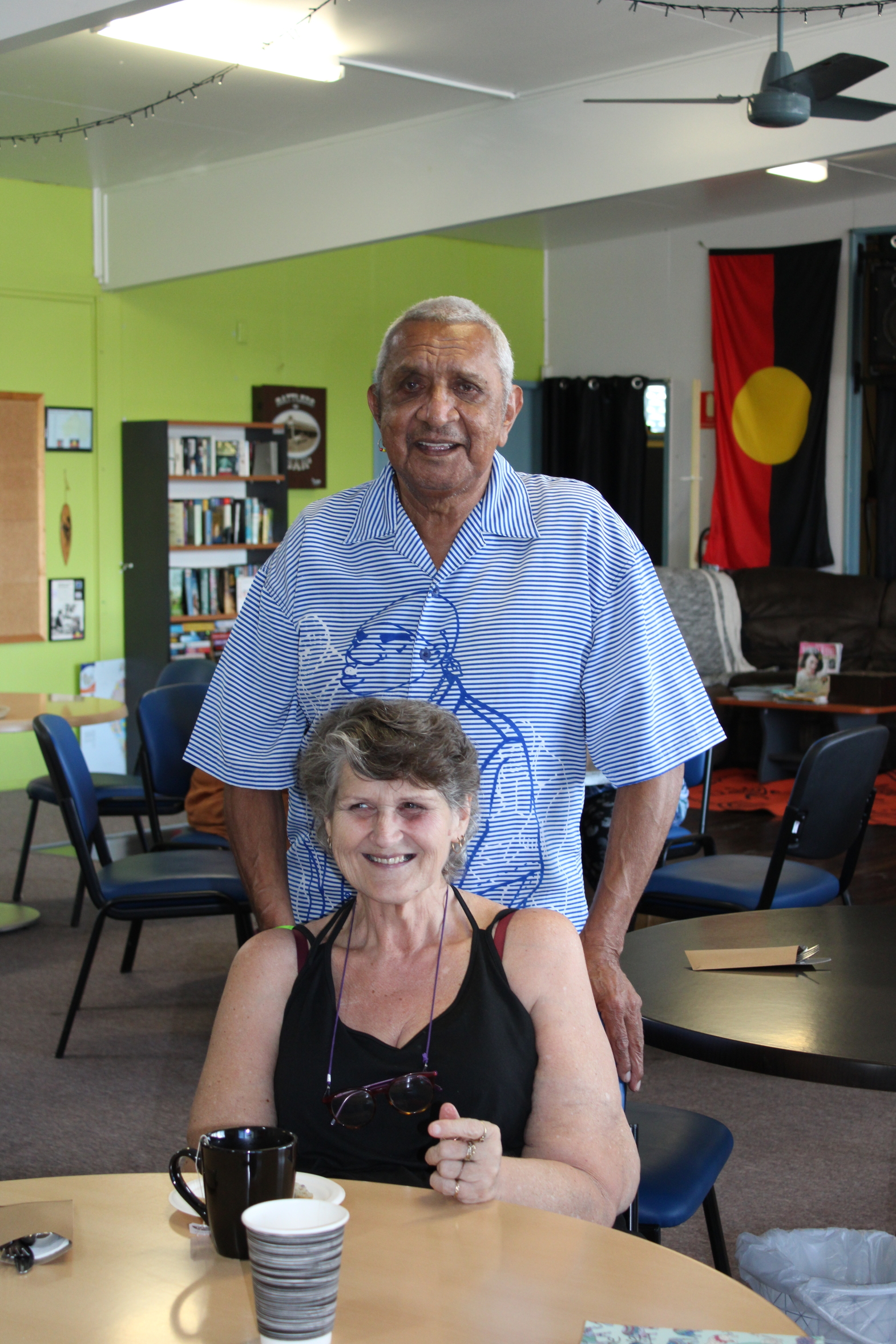 Woman sits at a table with a man standing behind her