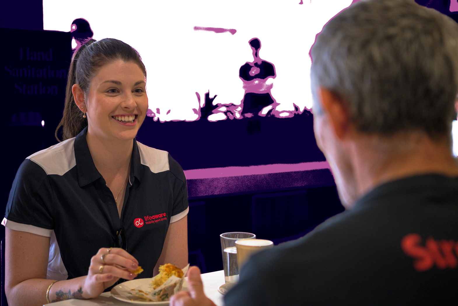 Life Aware staff member smiling at a participant while eating lunch