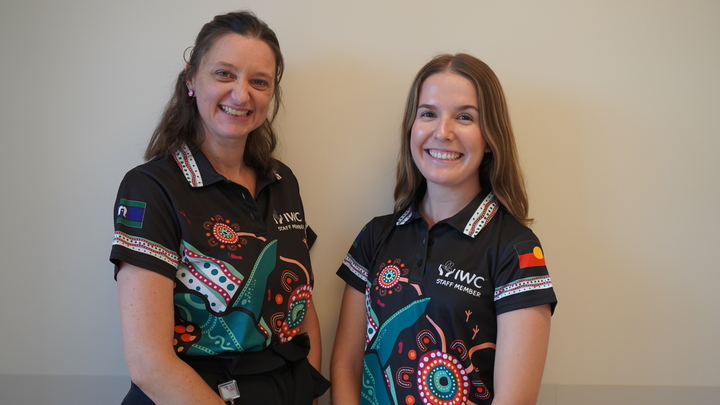 Meg and Zoe stand in front of a wall