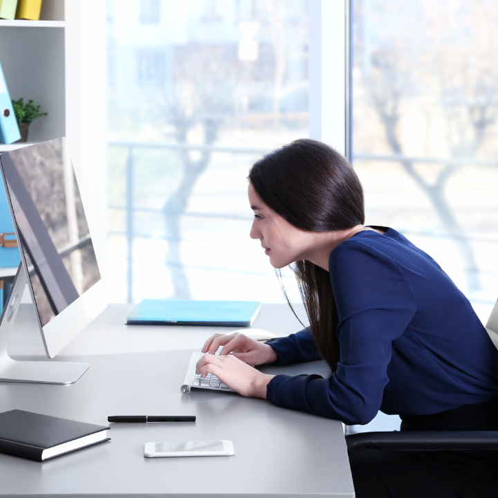 Woman sits slumped over in front of a computer at a desk