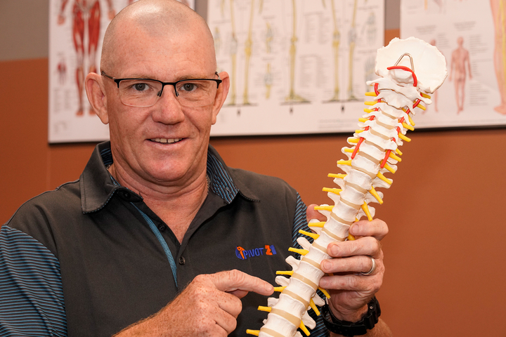 Physiotherapist holds a model of the spine