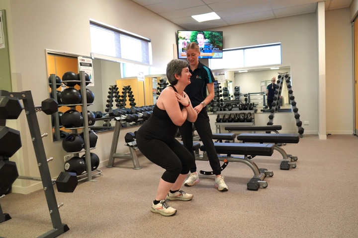 exercise physiologist guides woman in a squat