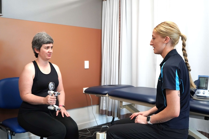 Exercise physiologist tests grip strength of woman