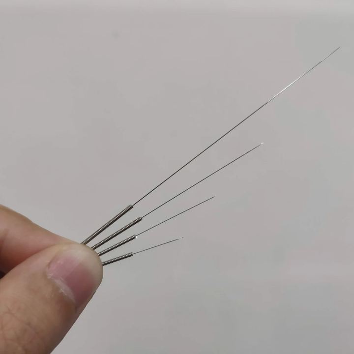 hand holding different sized acupuncture needles