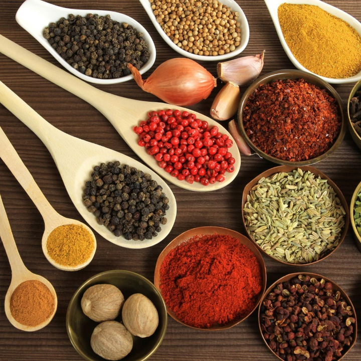 Variety of herbs and spices in wooden spoons and bowls.
