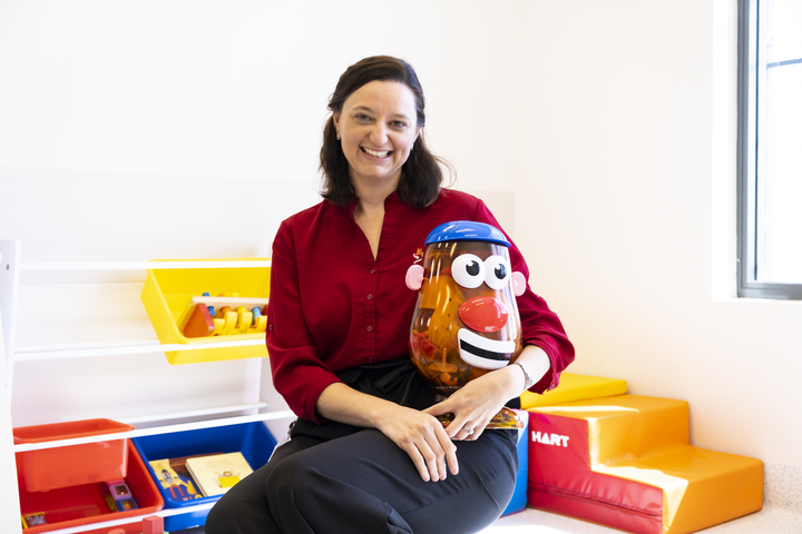 speech pathologist sits holding a mr. potato head