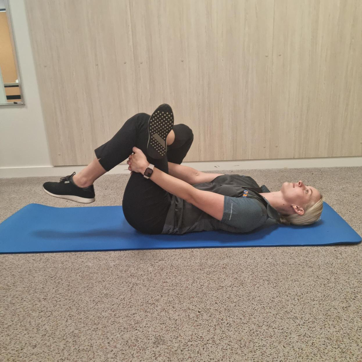 woman on exercise mat performing a piriformis stretch