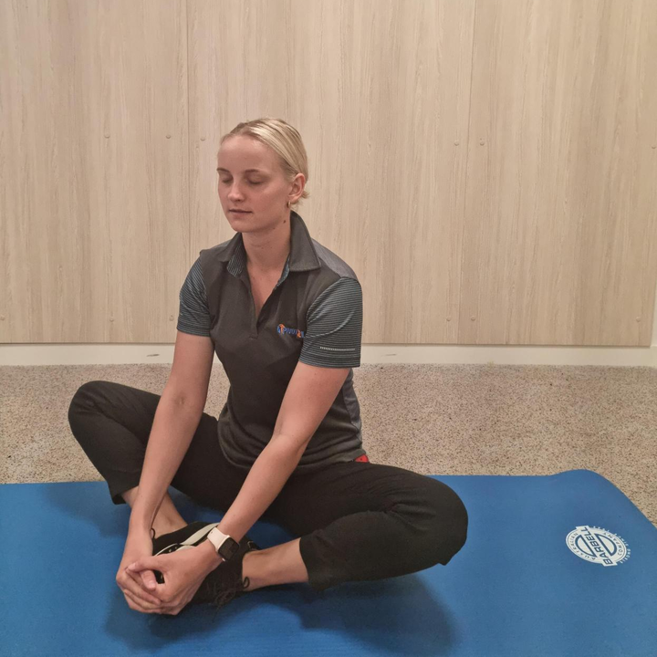 woman sitting in butterfly stretch on an exercise mat