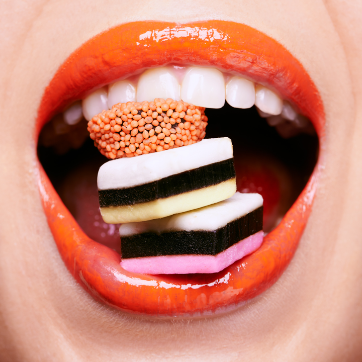 Mouth with 3 lollies stacked between teeth.