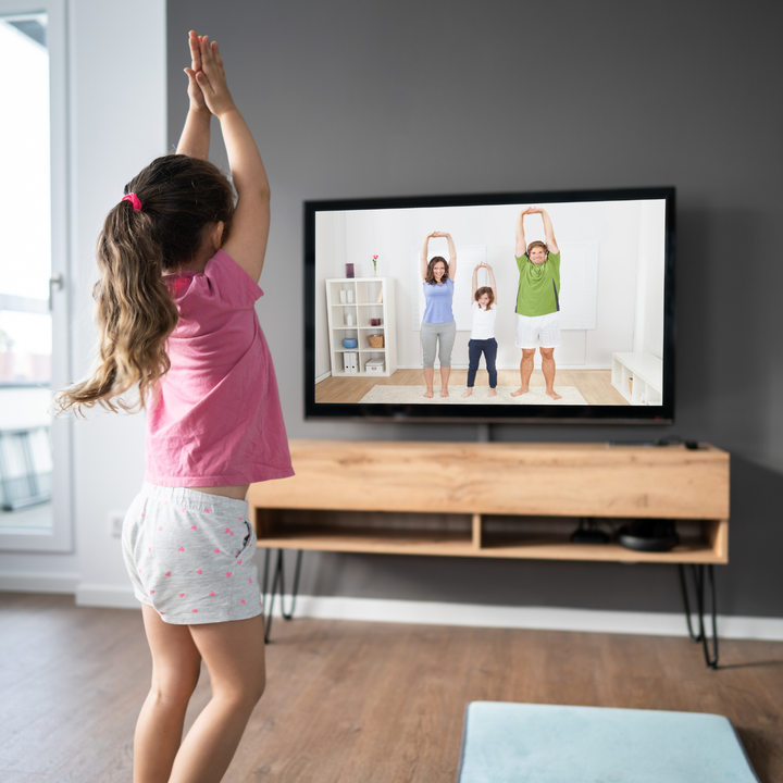 young girl dances along with tv show on television