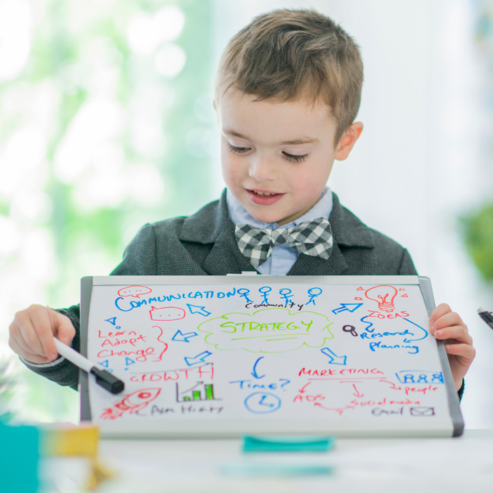 young boy holds whiteboard with visuals and text