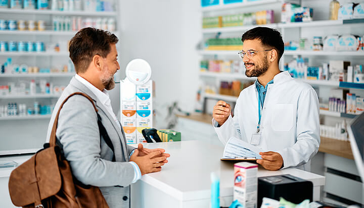 Pharmacist helps man with medication in brightly lit pharmacy