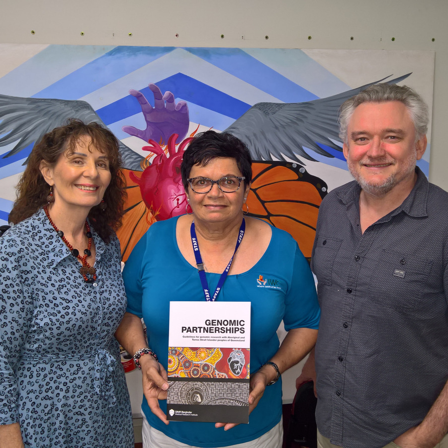 Group of 3 Individuals stand and face camera, middle person holds certificate.