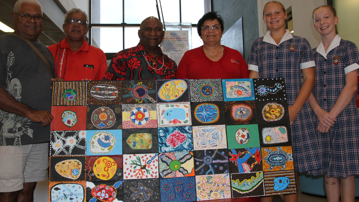 First Nations Community Members stand with students holding art piece