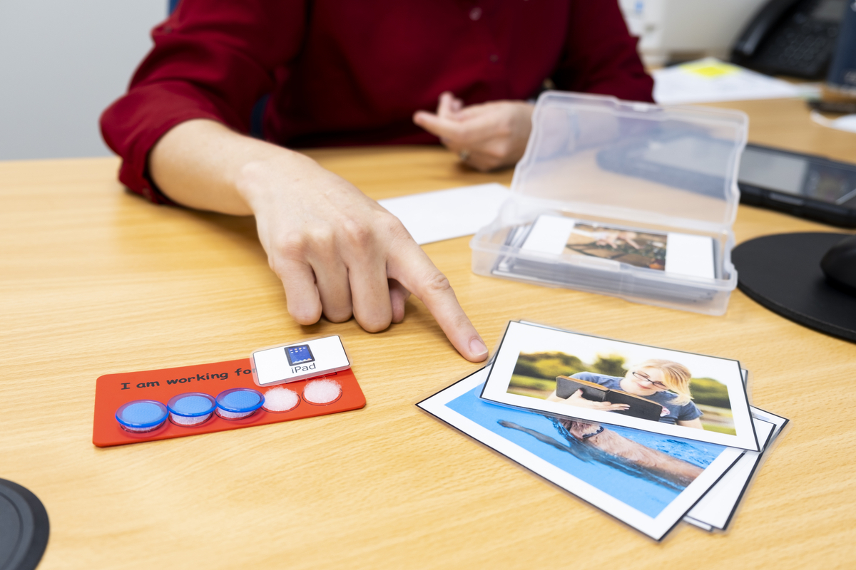 A Speech Pathologist points to flash cards on a desk
