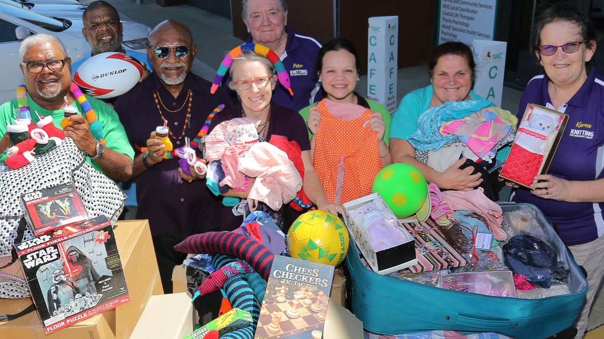 Staff stand with pile of donated Christmas Presents