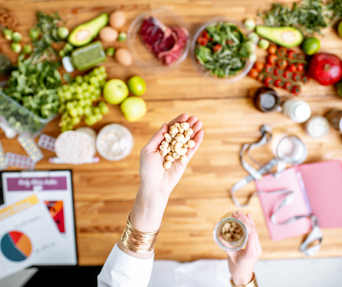 hand holds a handful of nuts over a workbench covered in fresh foods.