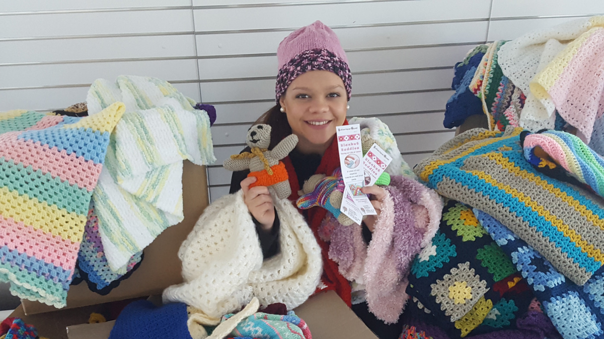 Girl sits among knitted products