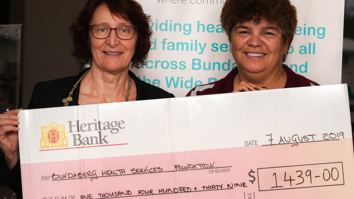 2 women hold novelty cheque showing donation amount.
