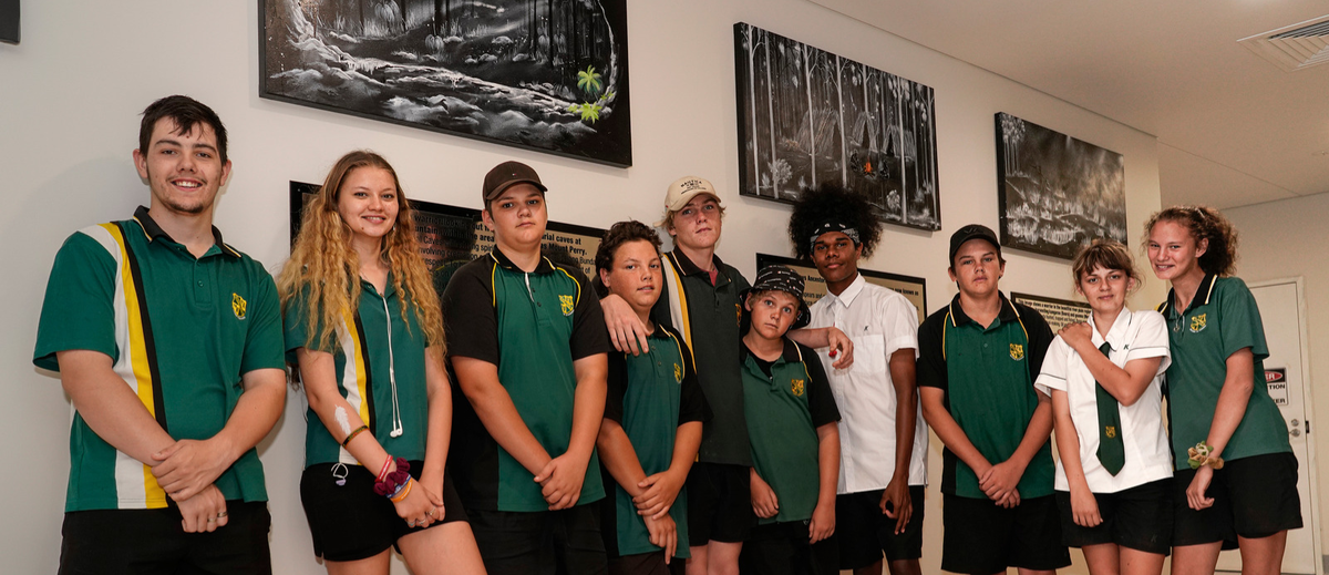 A group of High School students stand in hallway in front of cultural paintings