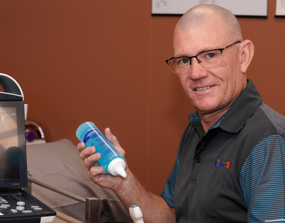 Scott Davis, Physiotherapist holds an ultrasound wand and ultrasound gel