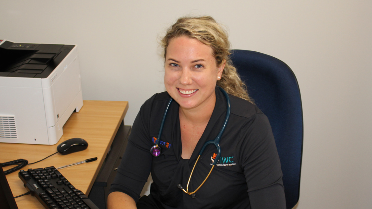 Speech Pathologist sits at her desk, smiling at the camera