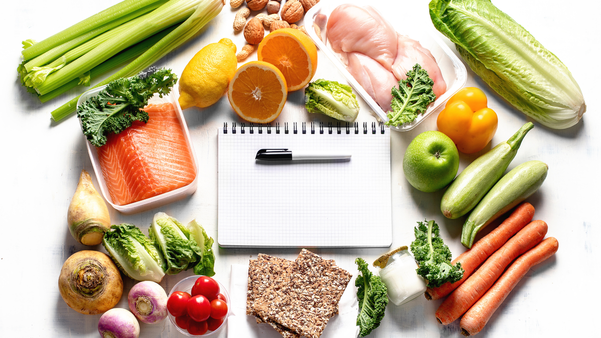 Selection of Foods surrounding a notepad and pen