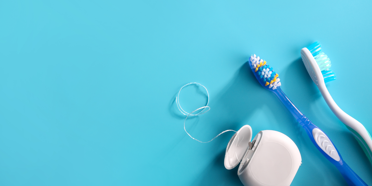 Two Toothbrushes and dental floss sit on a Blue background