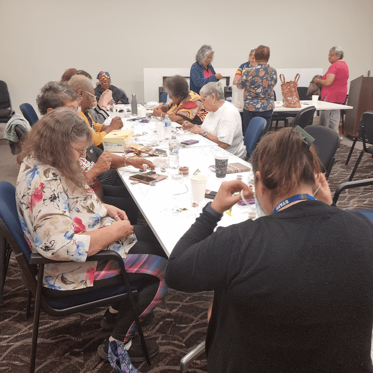 Group of women sit at tables doing crafts