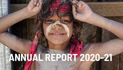 Young indigenous boy with red headpiece with text over top reading Annual Report 2020-2021